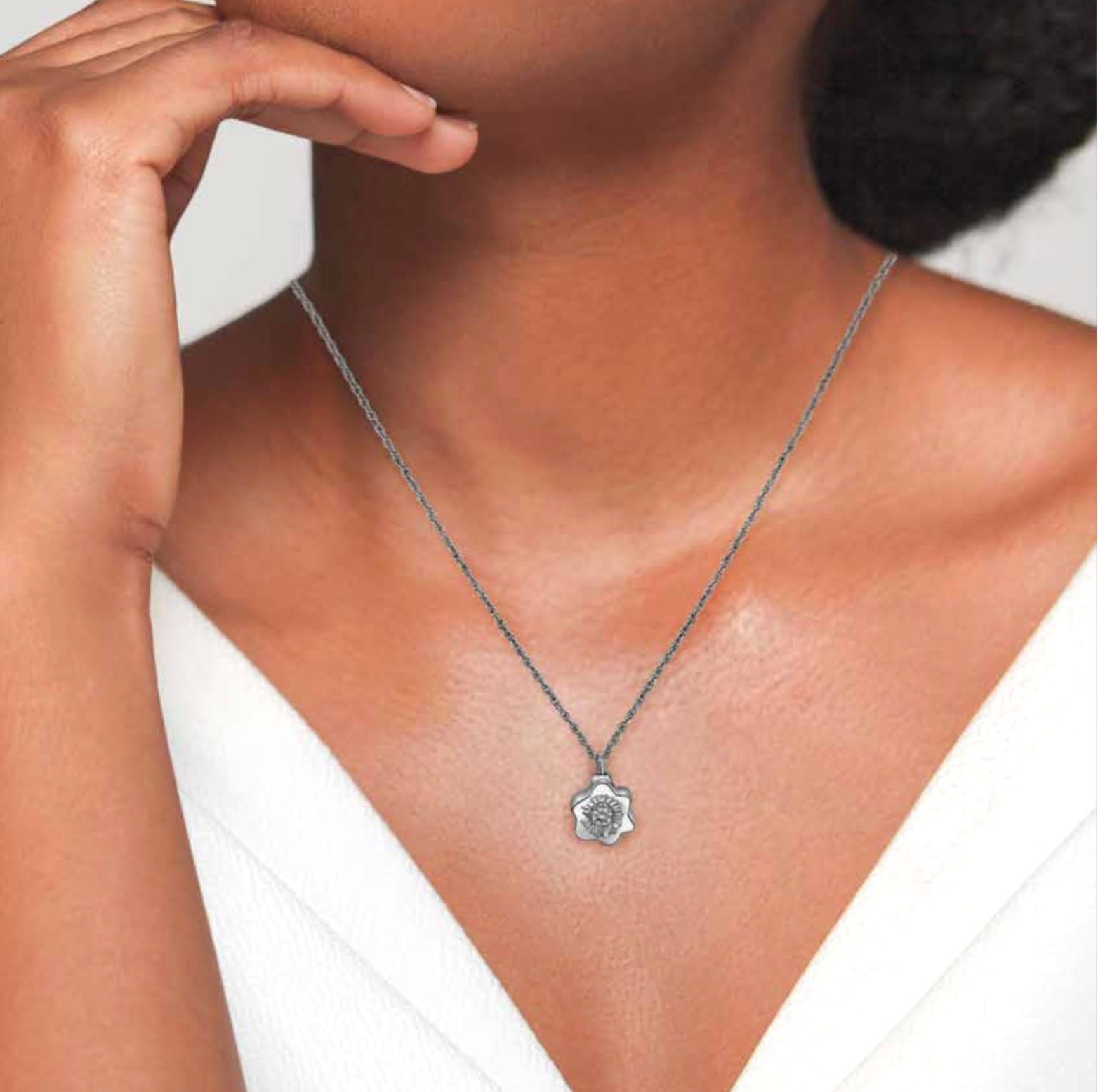 Silver pendant necklace on a person wearing a white V-neck top