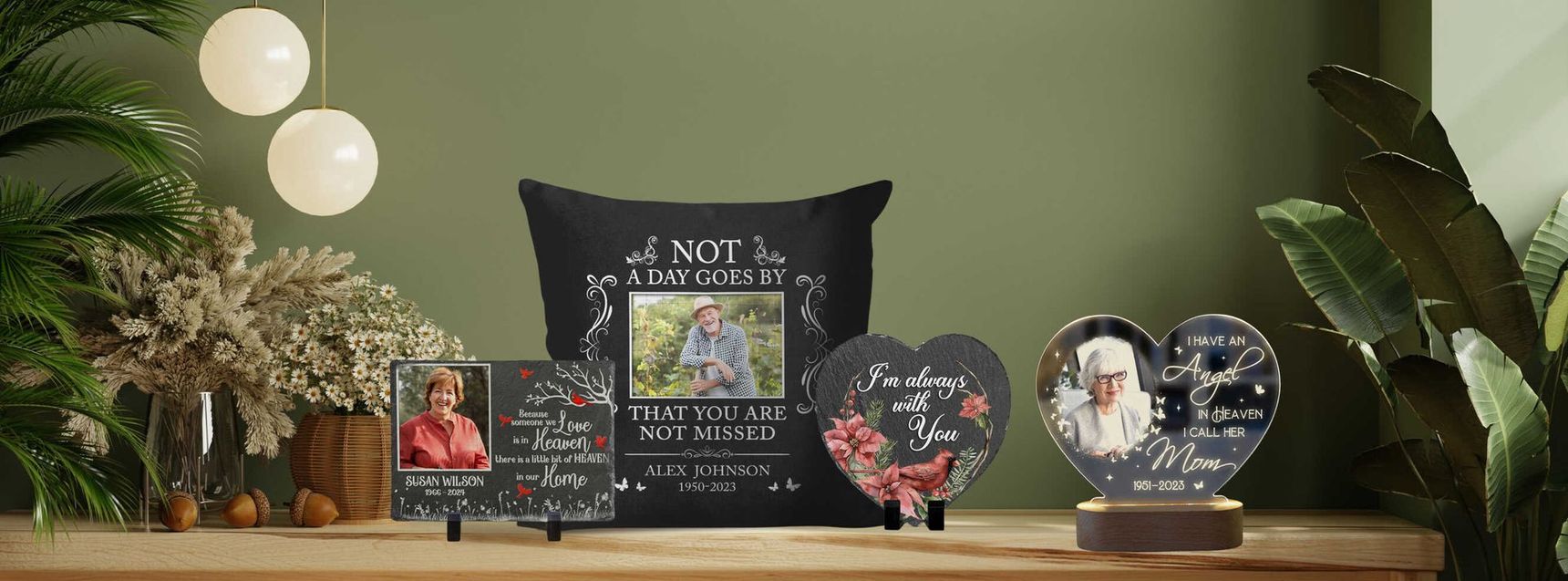 Memorial display with candles, flowers, framed photos, and heart-shaped keepsakes on a table against a green wall
