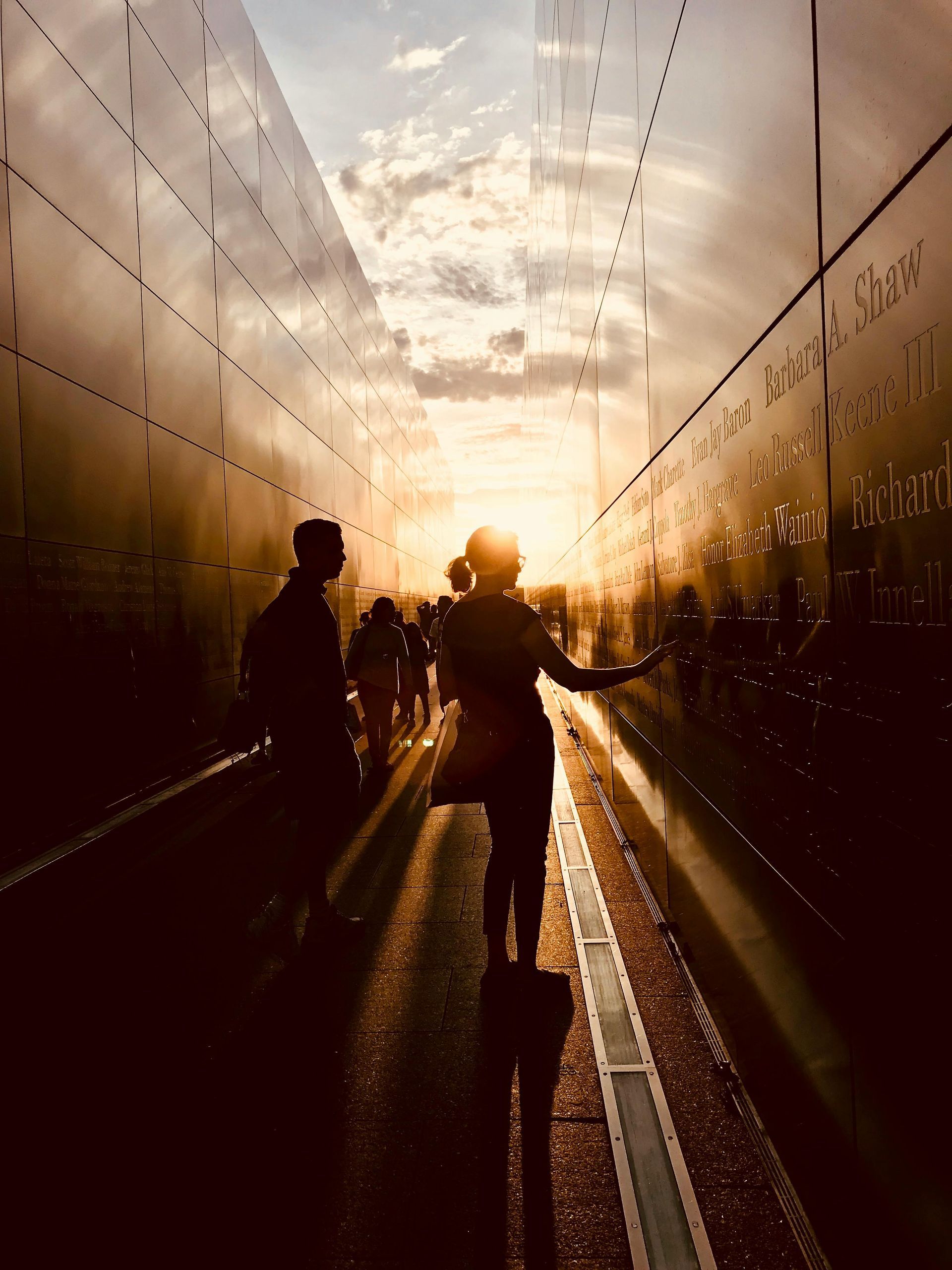 Silhouetted couple walking through a sunlit tunnel at sunset, holding hands.