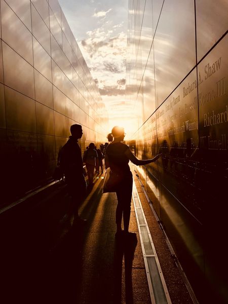Two silhouetted people walking through a sunlit tunnel at sunset