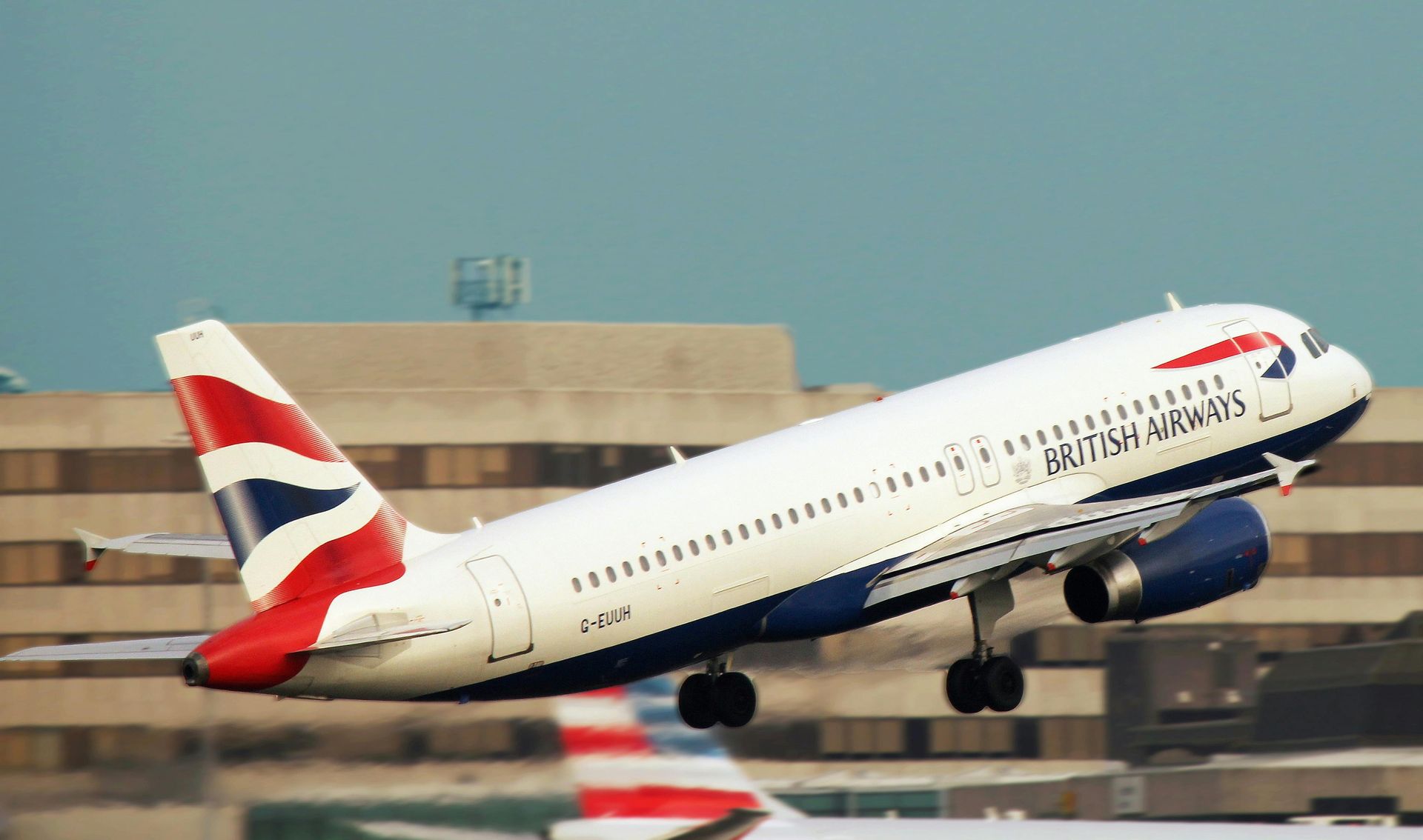 British Airways jet taking off, angled upward with landing gear extended against a blue sky