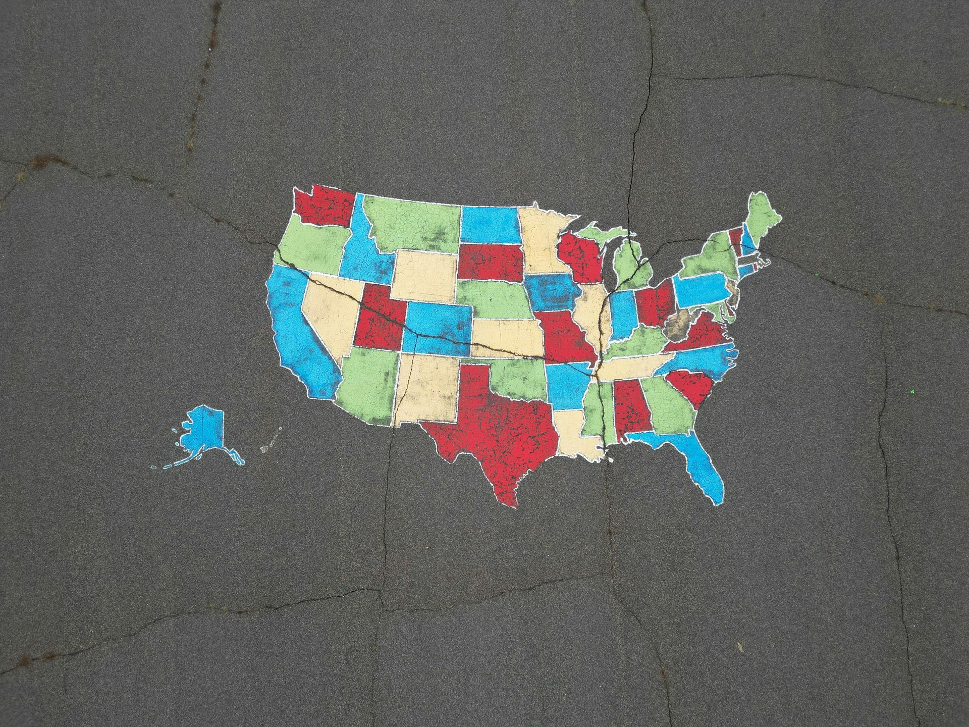 Colorful map of the United States made from small quilt-like patches on dark pavement.