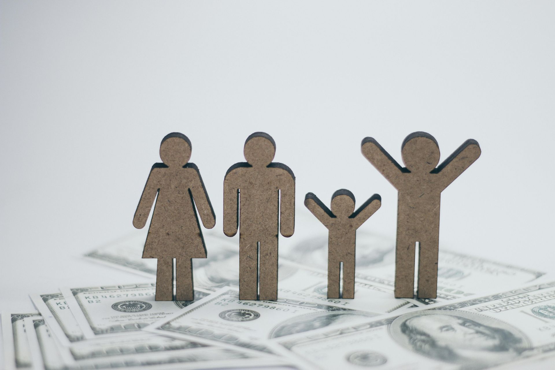 Paper cutout family figures standing on dollar bills, symbolizing finances and family budget