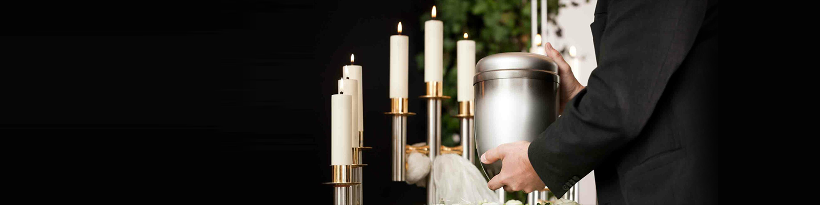 Person placing a candle on a church altar beside lit candles and a silver vessel