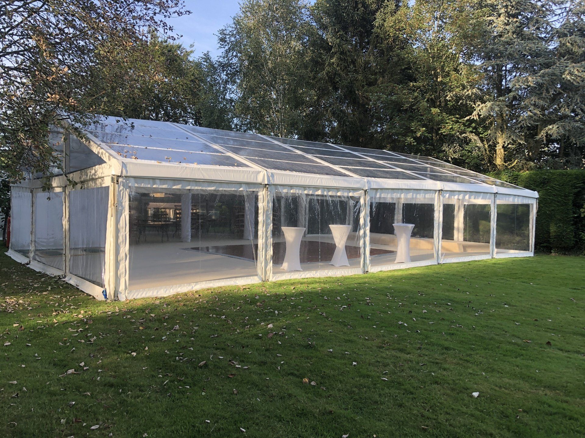 A large clear tent is sitting in the middle of a lush green field.