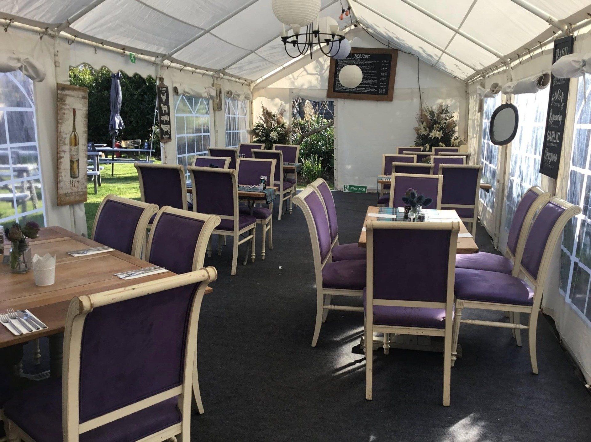A restaurant with purple chairs and tables under a tent