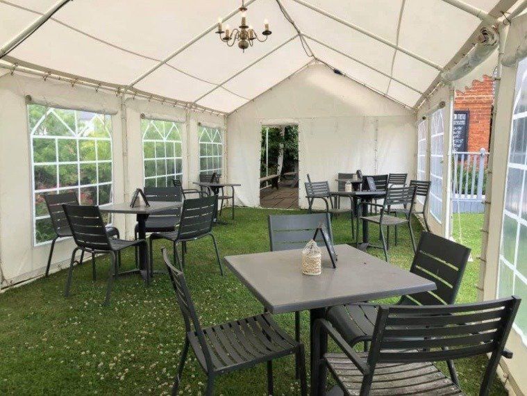 A tent with tables and chairs inside of it.