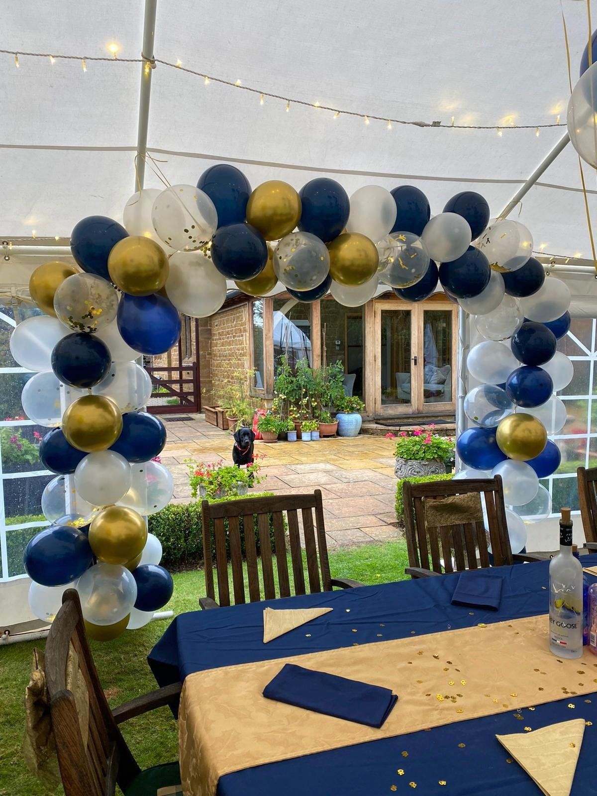 A table and chairs are decorated with blue and gold balloons.