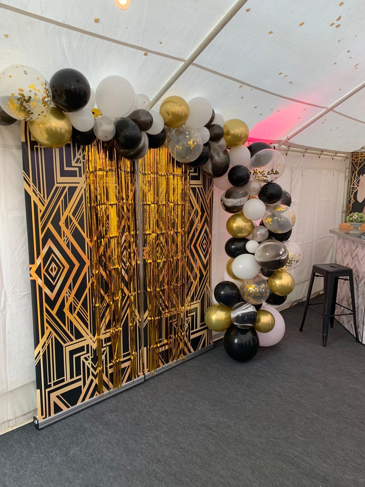 A room filled with balloons and a gold curtain.