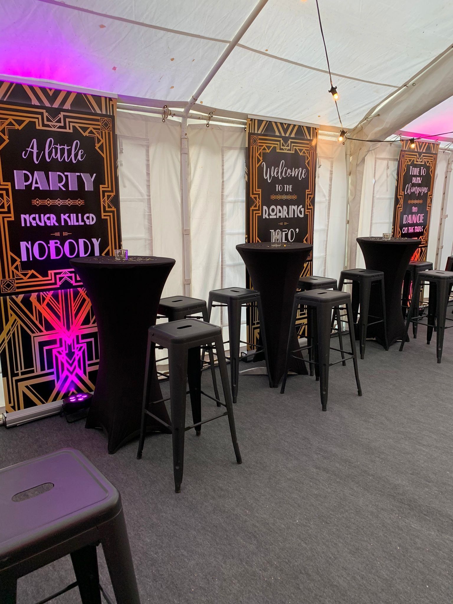 A row of tables and stools are lined up in a tent.