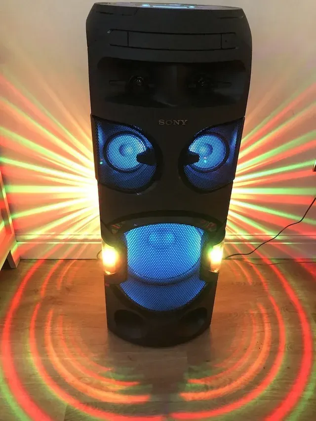 A sony speaker with lights on it is sitting on a wooden floor.