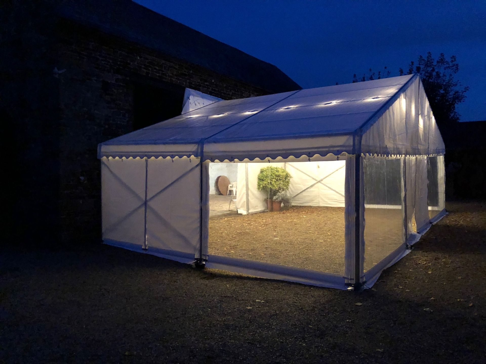 A tent is lit up at night and has a clear roof