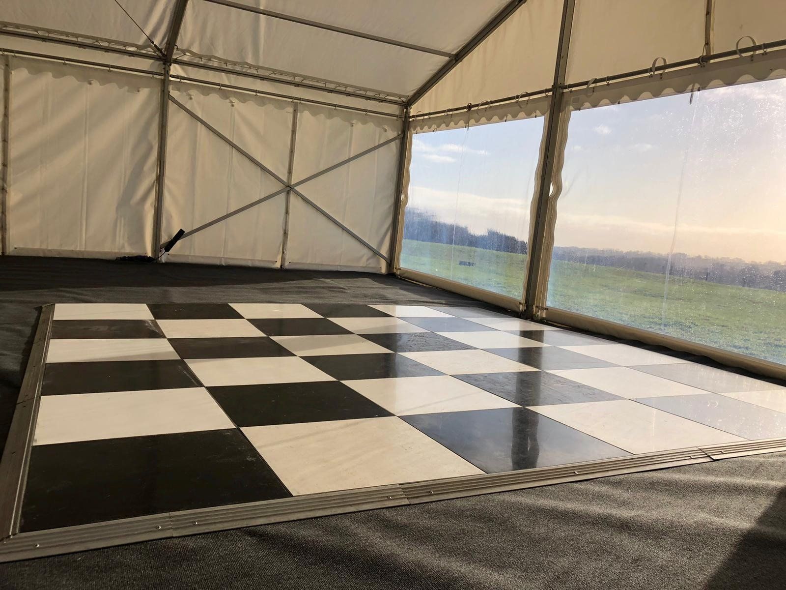 A black and white checkered dance floor in a tent.