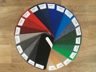 A circular display of different colored carpets on a wooden floor.