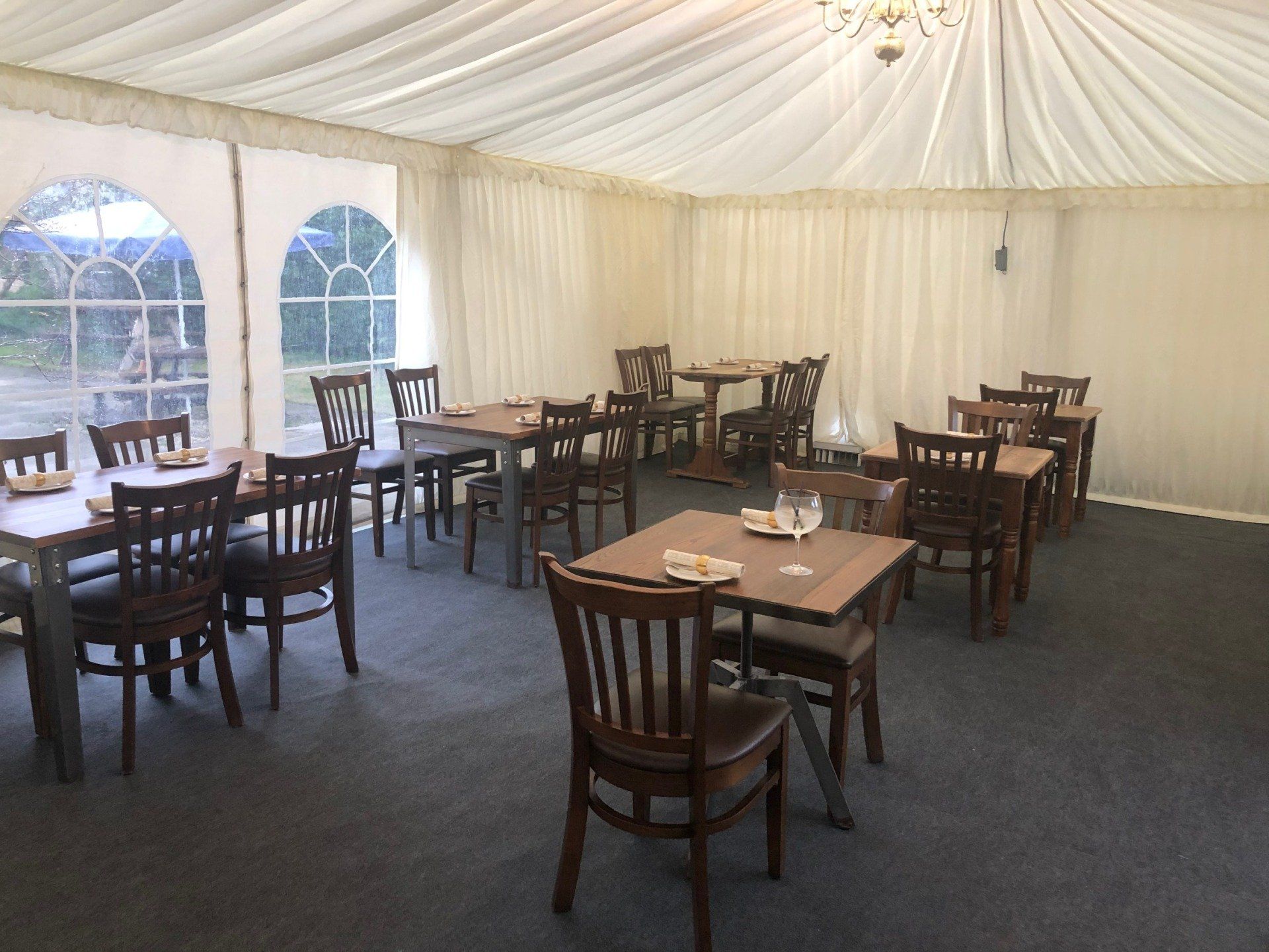 A restaurant with tables and chairs under a tent.