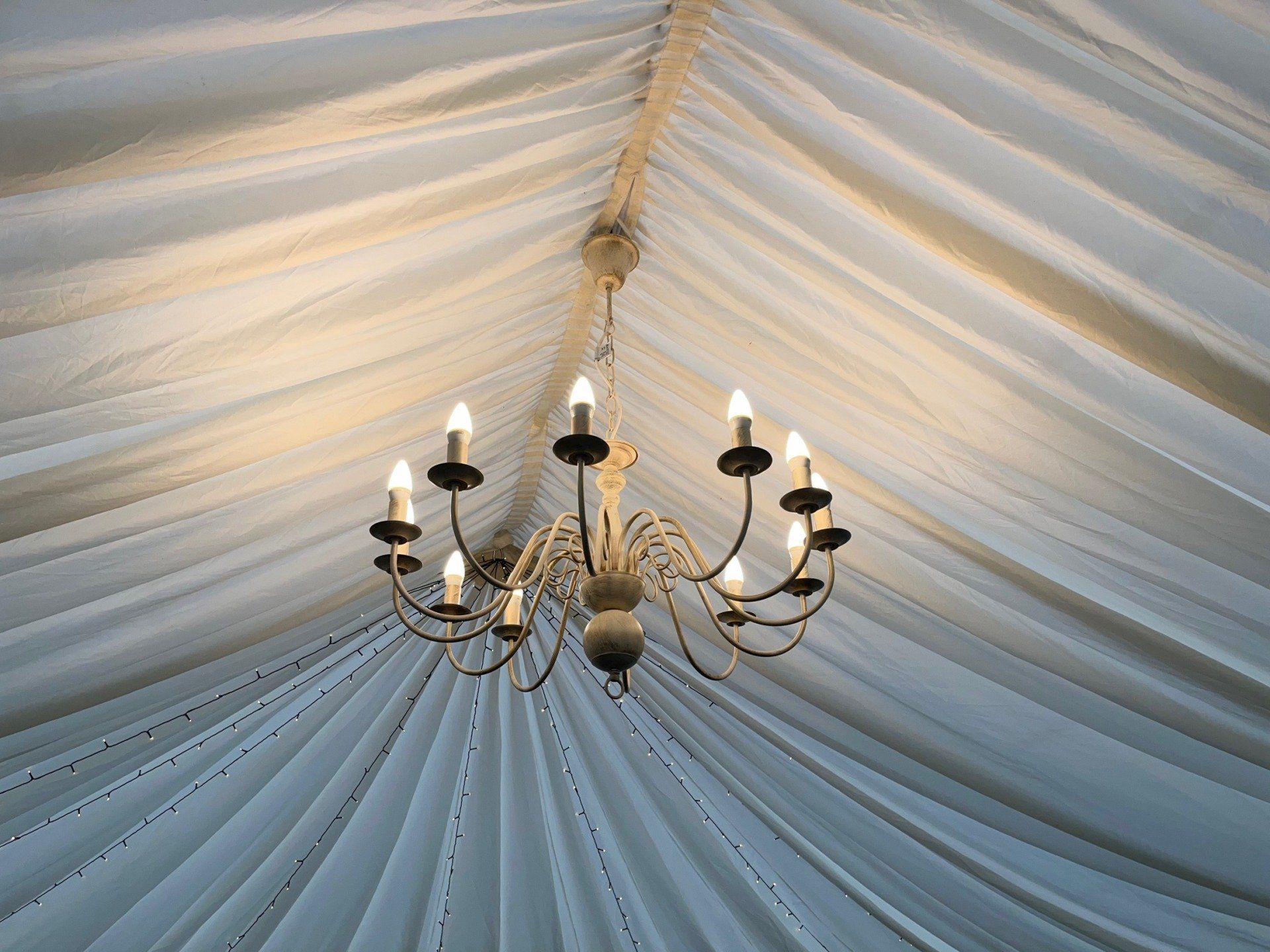 A chandelier is hanging from the ceiling of a tent.