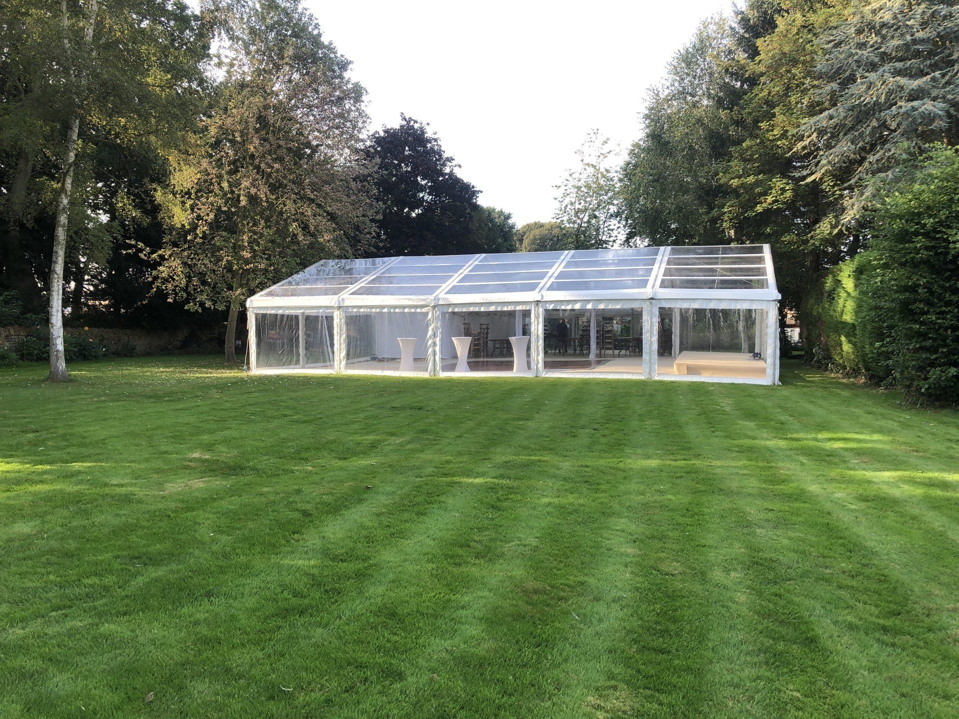 A large clear tent is sitting in the middle of a lush green field.