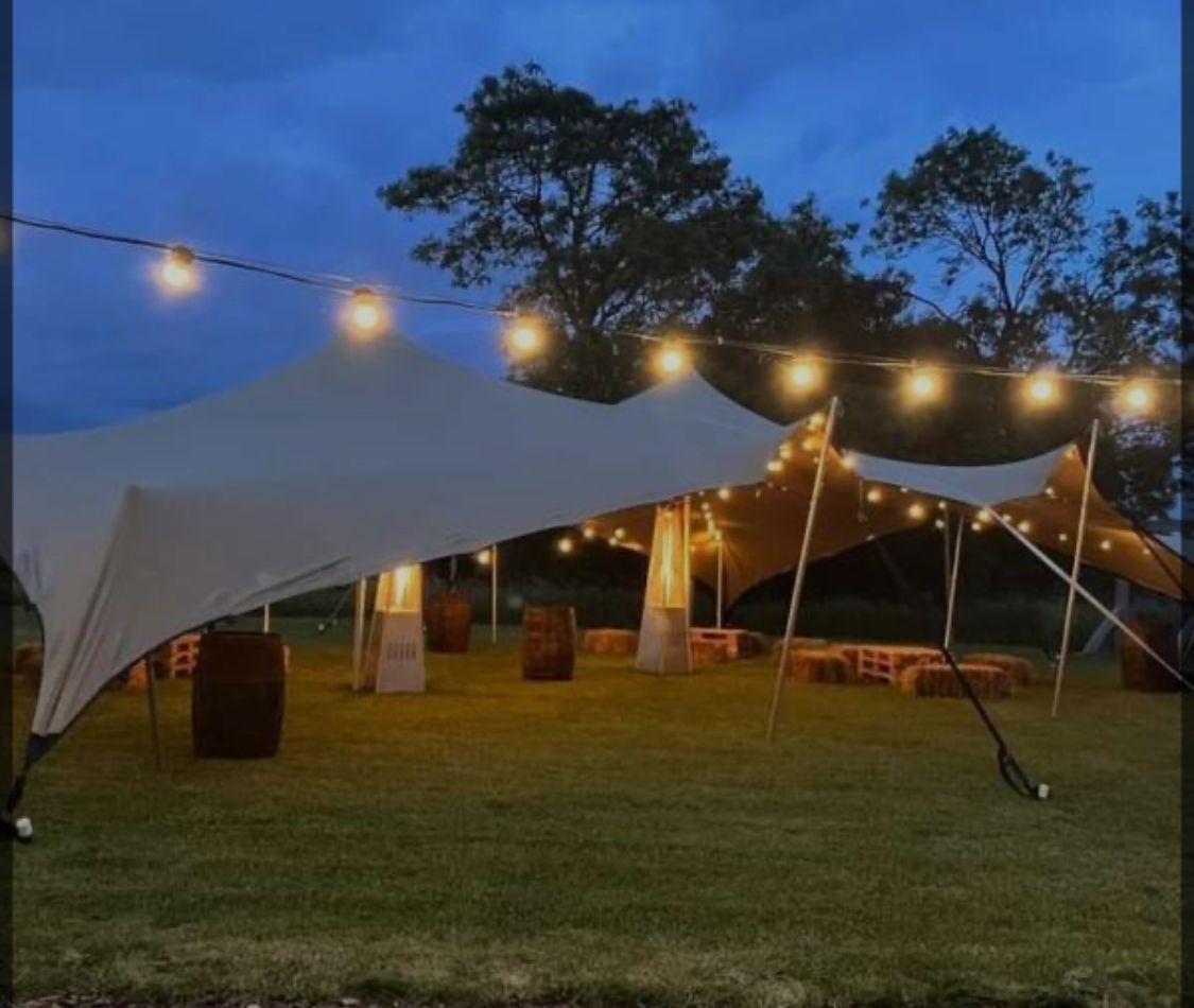A large white tent is sitting in the middle of a grassy field.