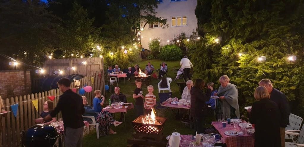 A group of people are gathered around a fire pit in a backyard at night.