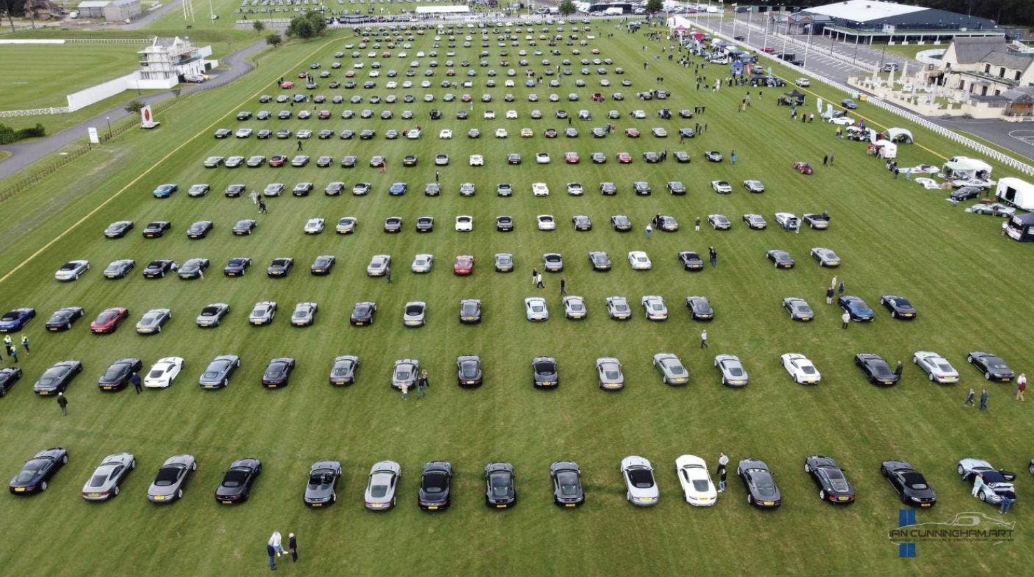 A bunch of cars are parked in a grassy field