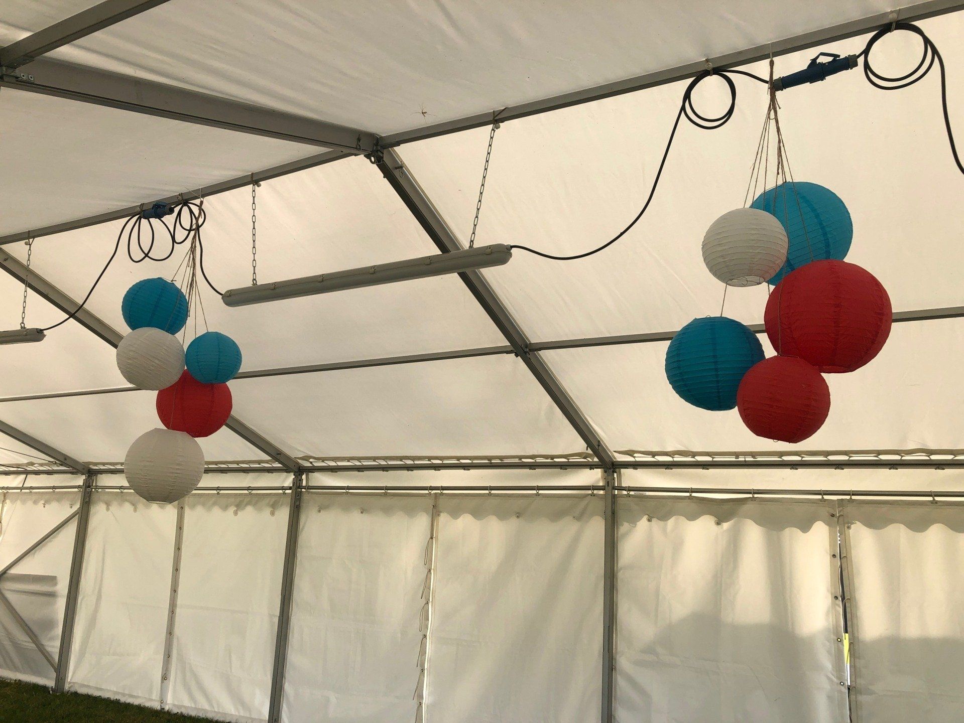 Red white and blue balloons are hanging from the ceiling of a tent
