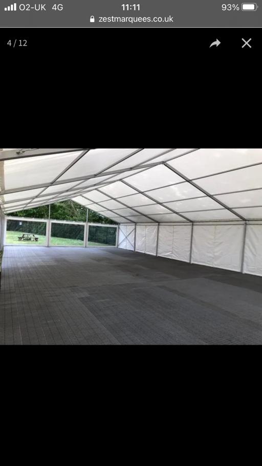 A large empty tent with a black floor and a white roof.