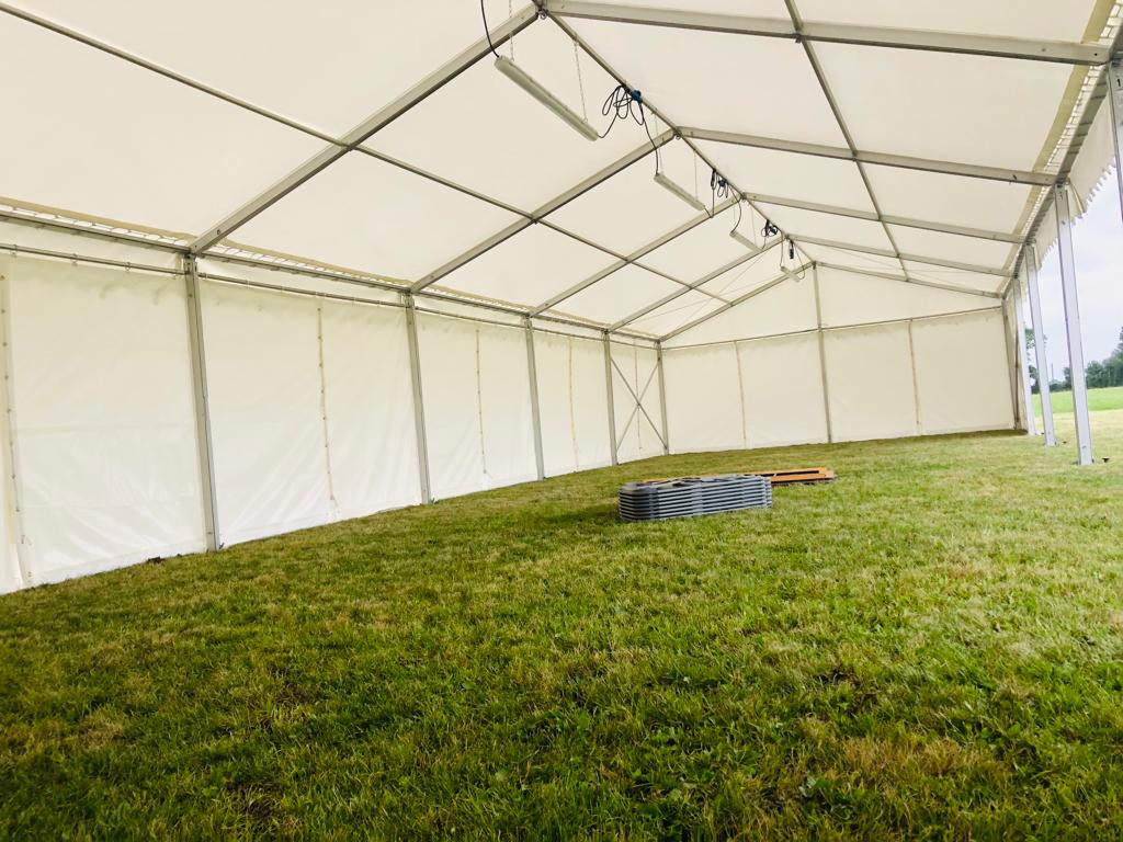 A large white tent is sitting on top of a lush green field.