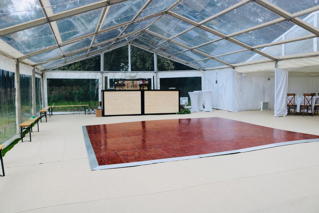 A large clear tent with a red dance floor and a bar.