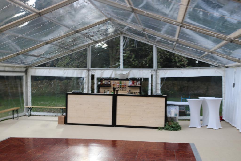 A clear tent with a bar and tables inside of it