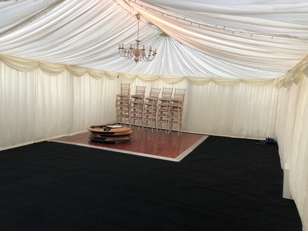 A large room with a dance floor and chairs under a tent.