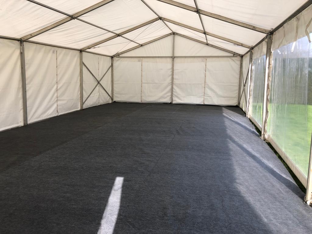 A large empty tent with a black carpet on the floor.