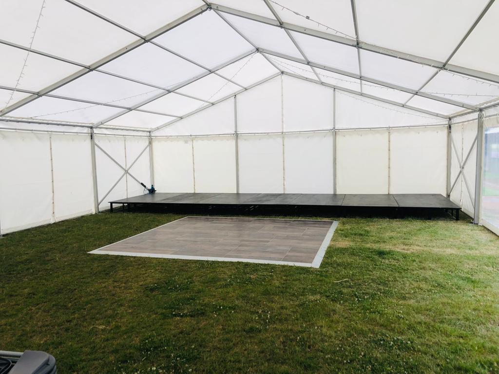 A large tent with a dance floor inside of it.