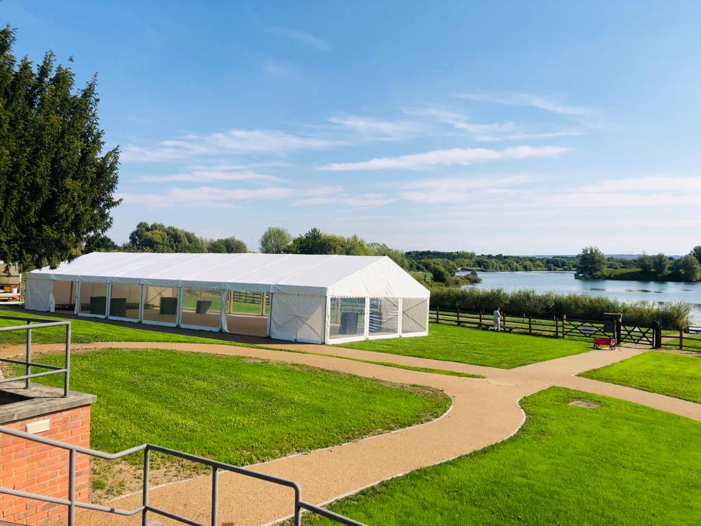 A large white tent is sitting in the middle of a lush green field.