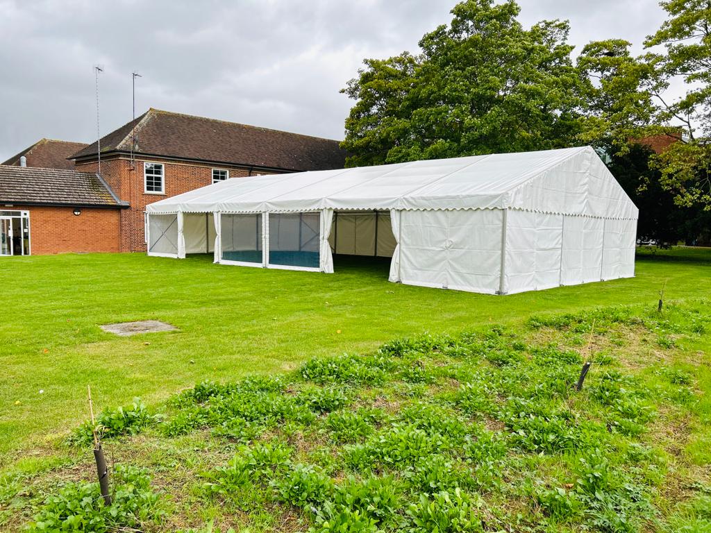 A large white tent is sitting in the middle of a lush green field.