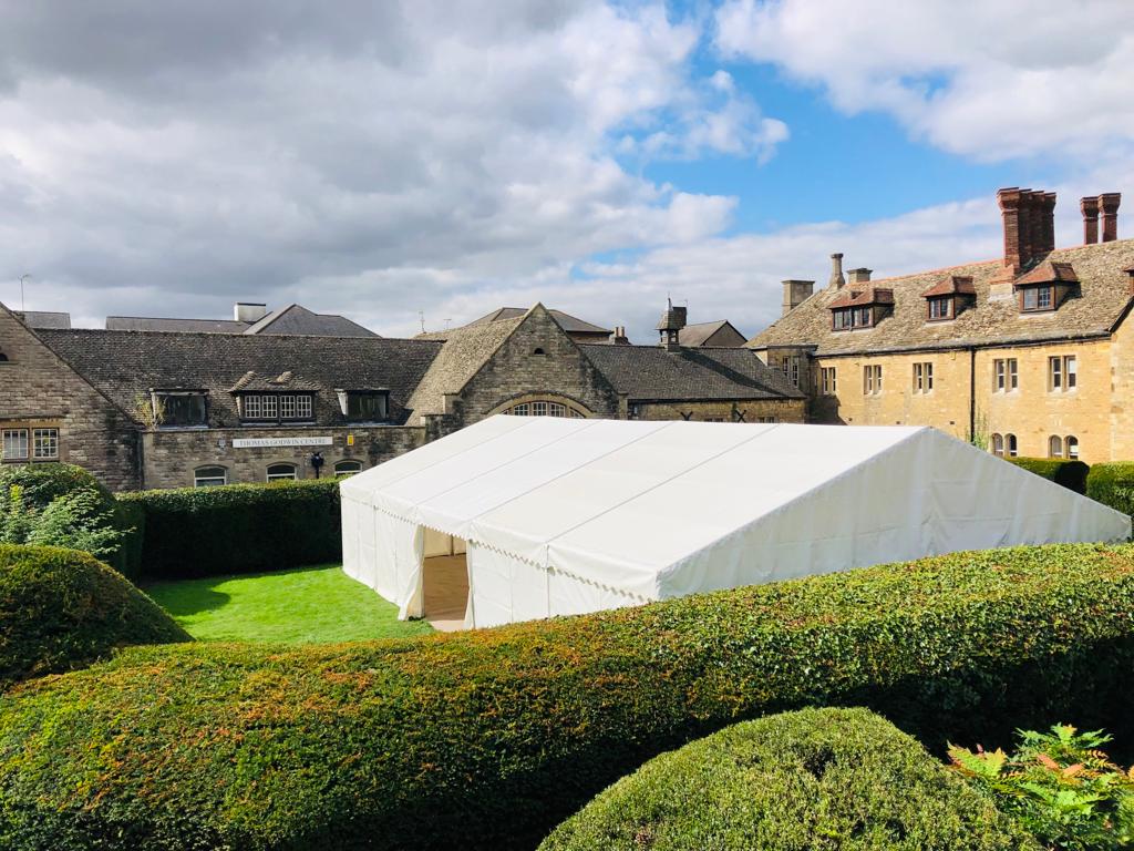 A large white tent is sitting in the middle of a lush green field.