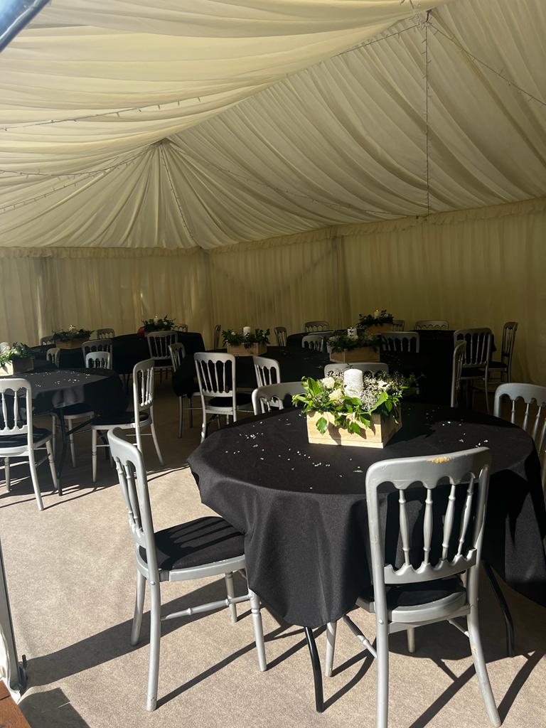 A large tent with tables and chairs set up for a wedding reception.