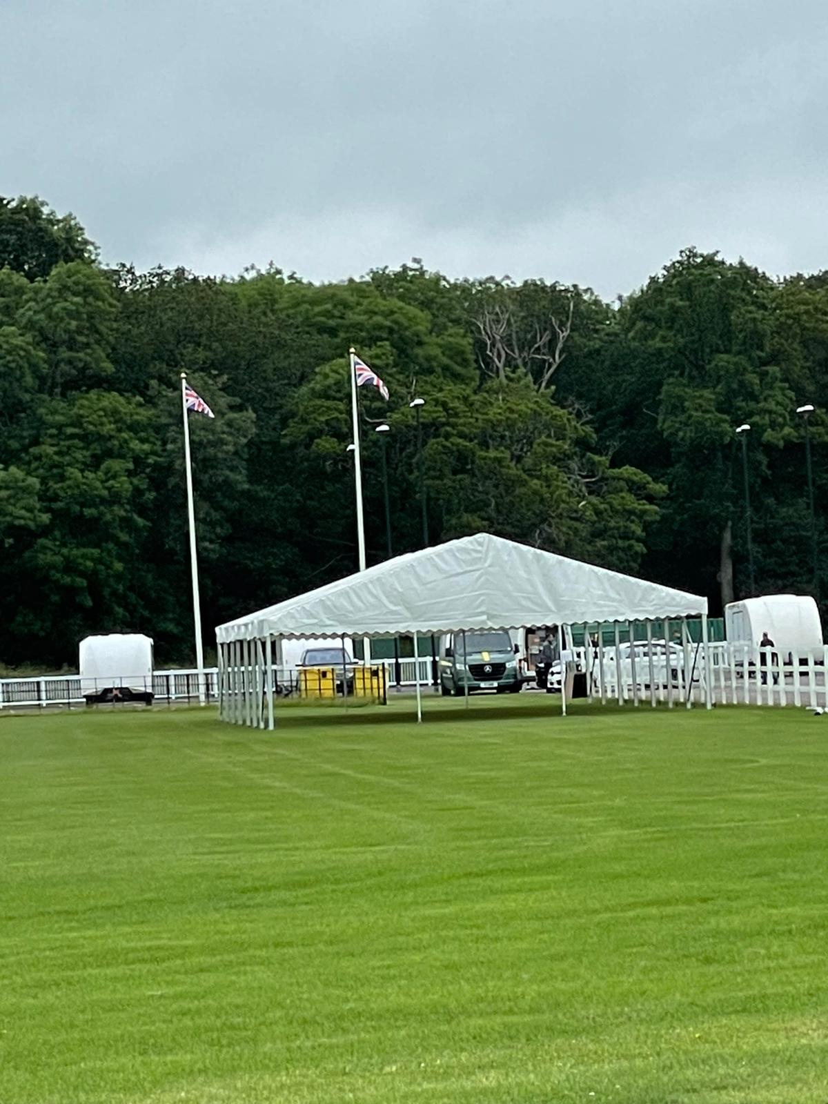 A large white tent is sitting in the middle of a lush green field.