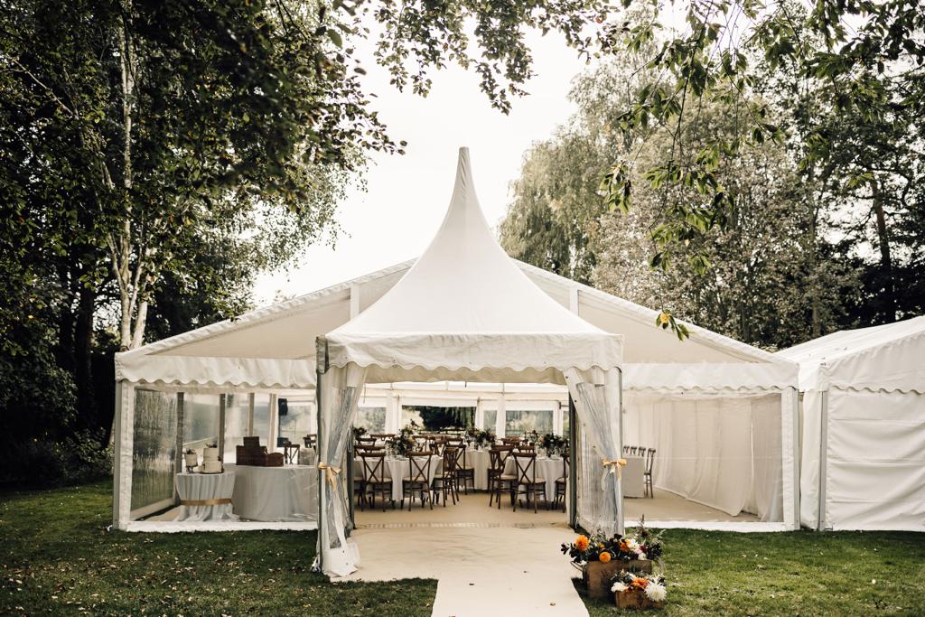 A large white tent with tables and chairs inside of it.