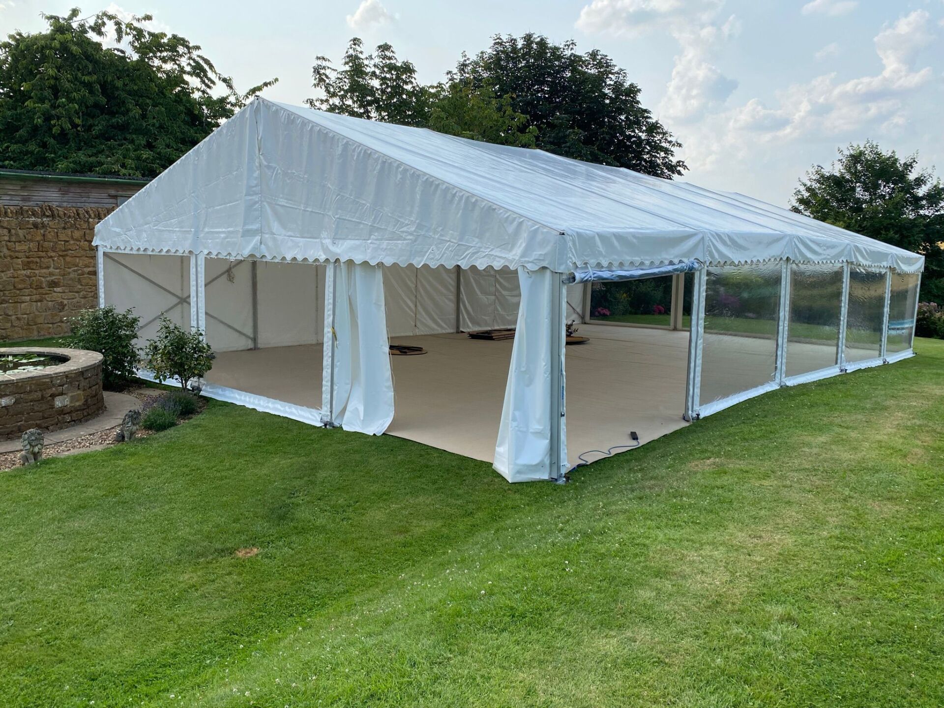 A large white tent is sitting in the middle of a lush green field.