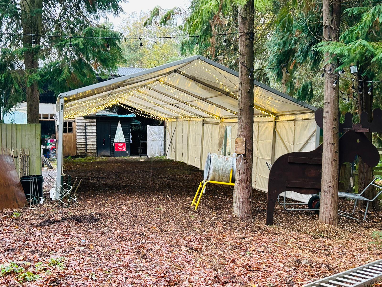 A horse statue is sitting under a tent in the woods.