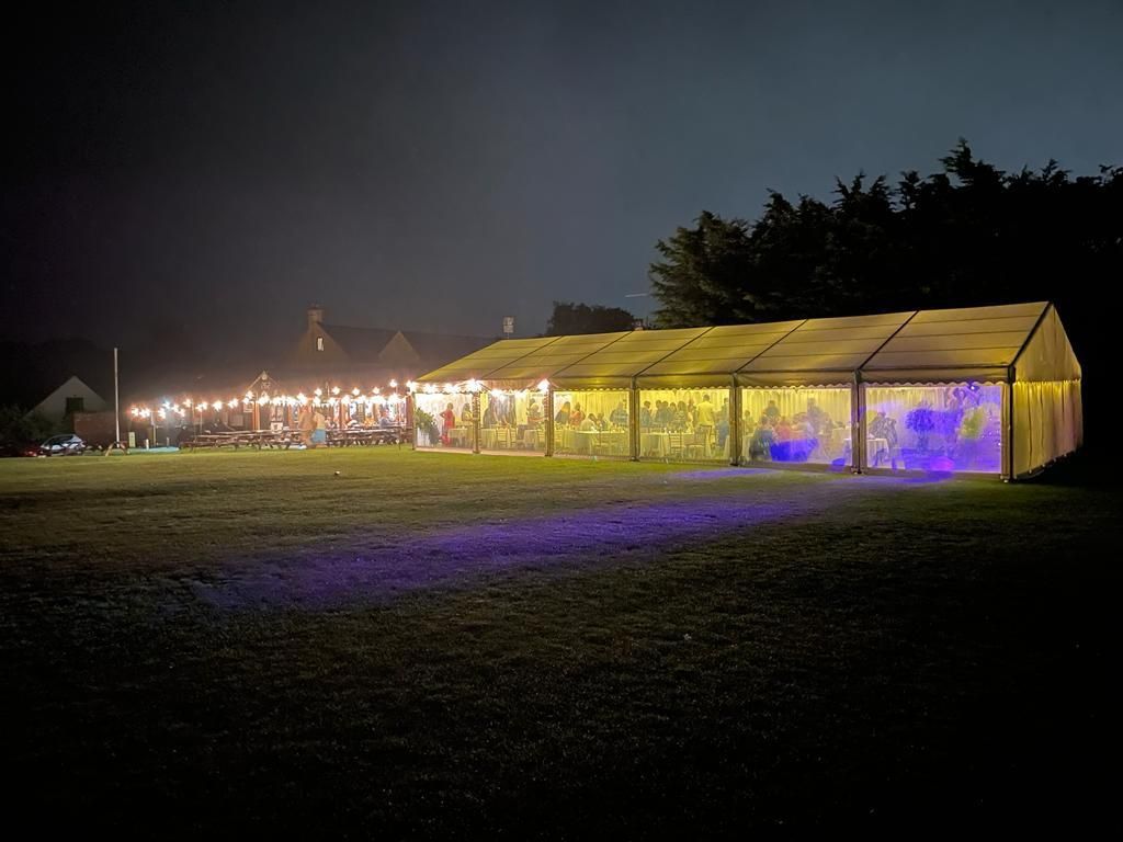 A large tent is lit up at night in a field.