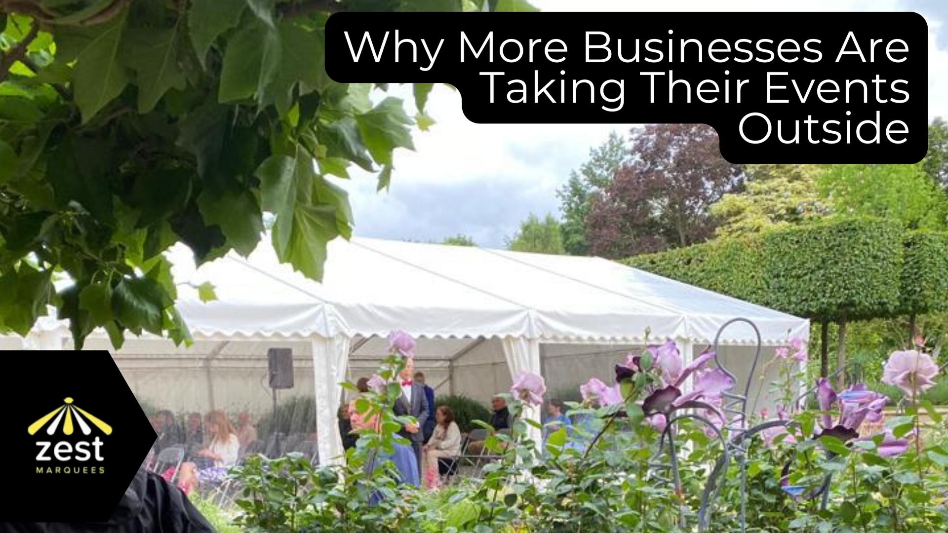 People seated at tables under a white event tent at an outdoor business gathering
