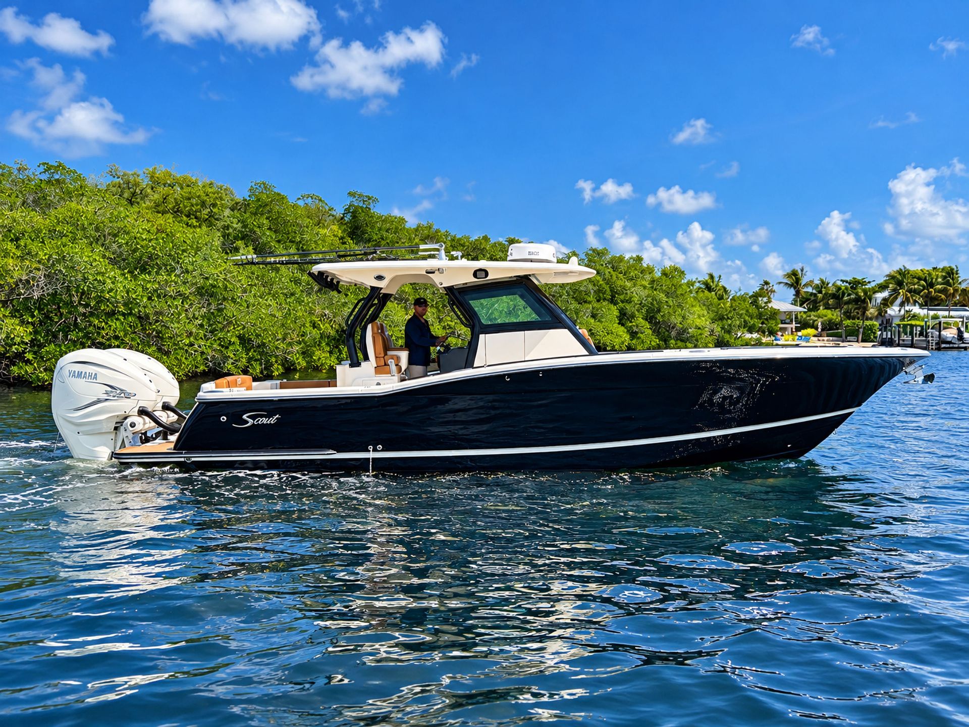 Black center-console boat cruising on blue water near a lush tropical shoreline under a bright sky