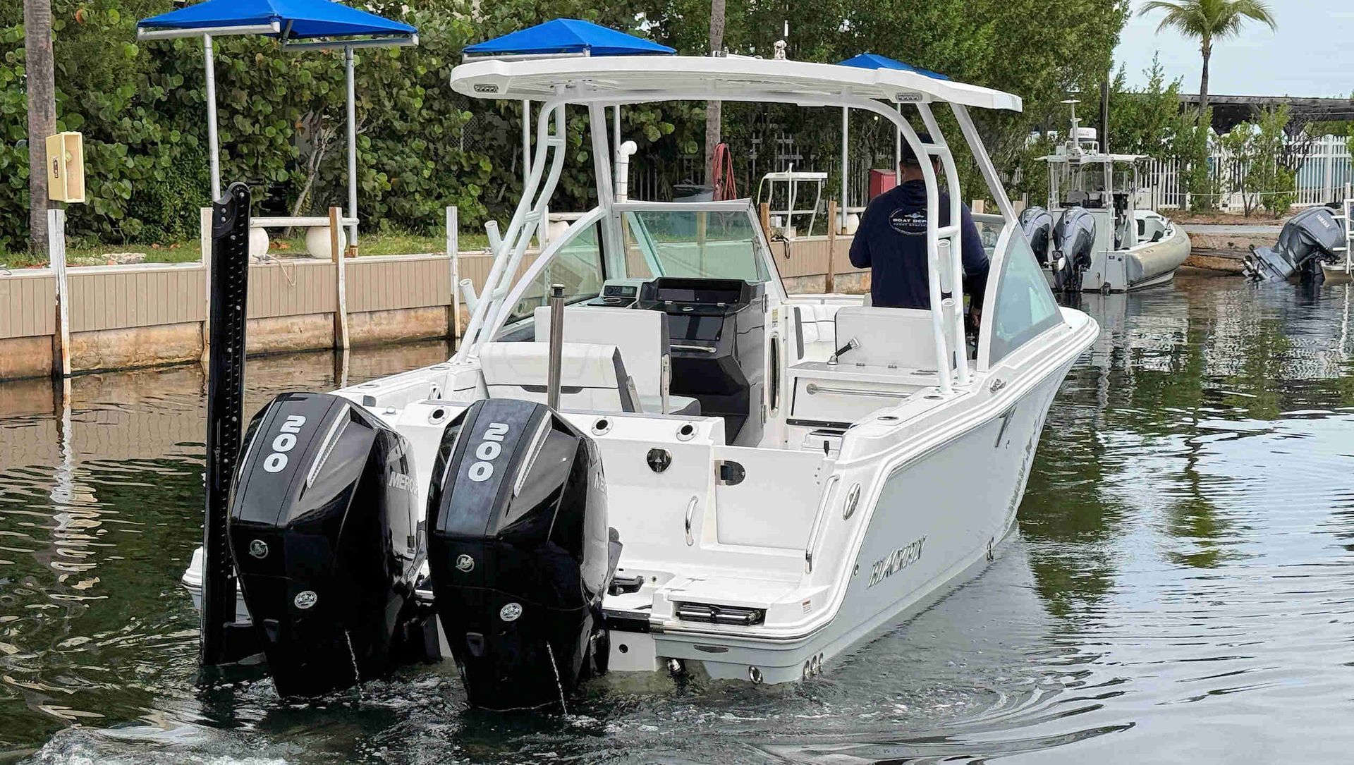 White dual-console boat with twin outboard motors docked in a marina