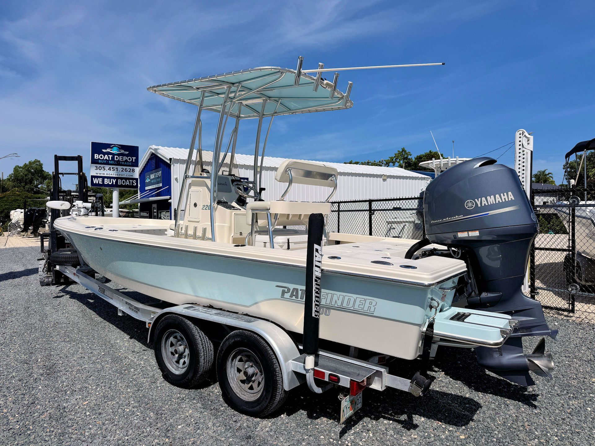 White center-console fishing boat on a trailer with outboard motor under a clear blue sky.
