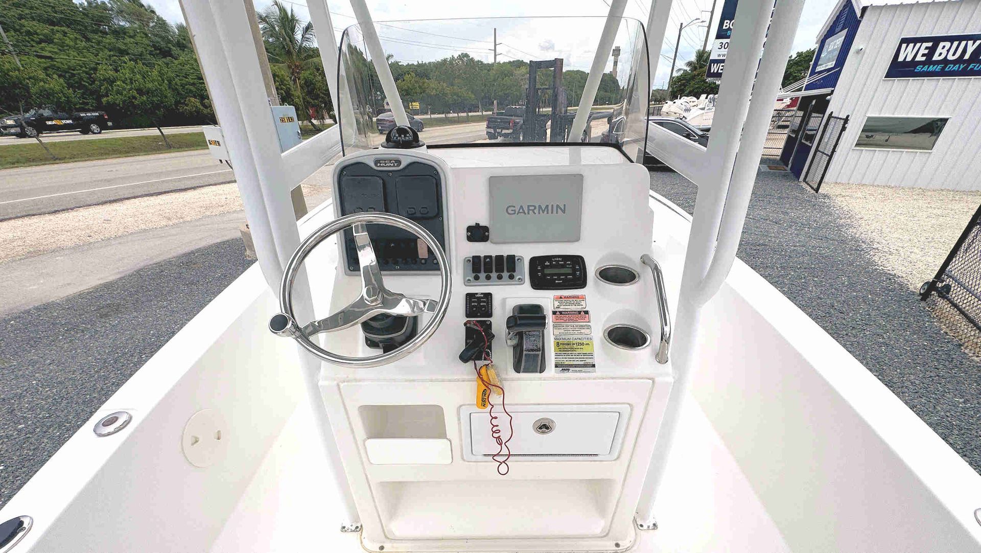 Boat helm with steering wheel, throttle, and control panel in a white console, viewed from the cockpit.