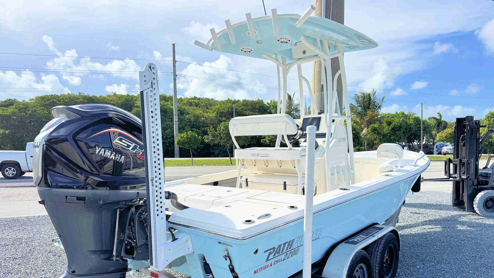 White fishing boat on a trailer with a large outboard motor and T-top canopy outdoors