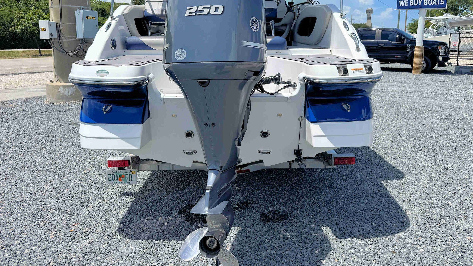 Rear view of a white and blue motorboat on a trailer in a gravel lot