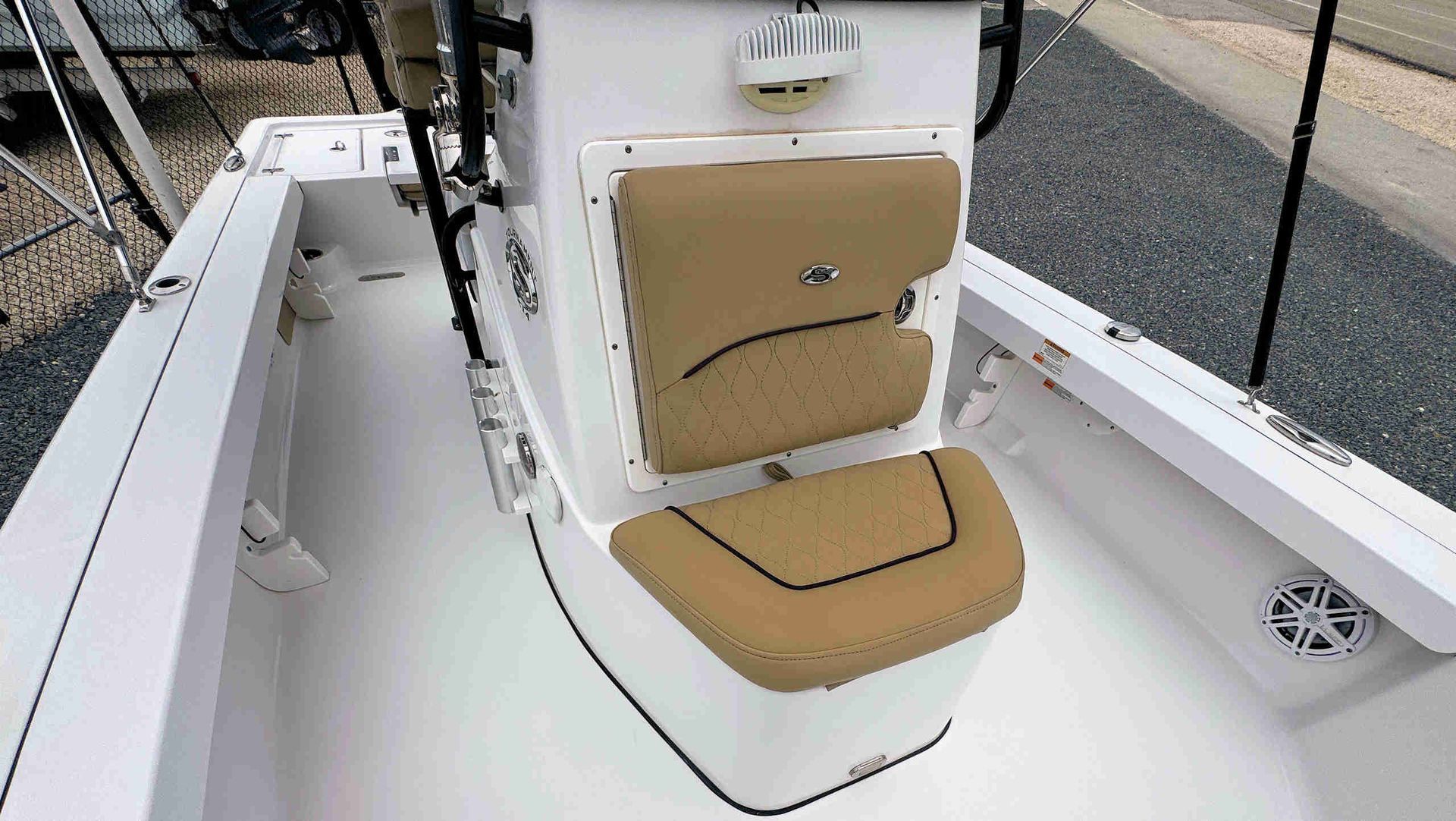 White boat helm seat with tan cushions on a deck near water and dock lines