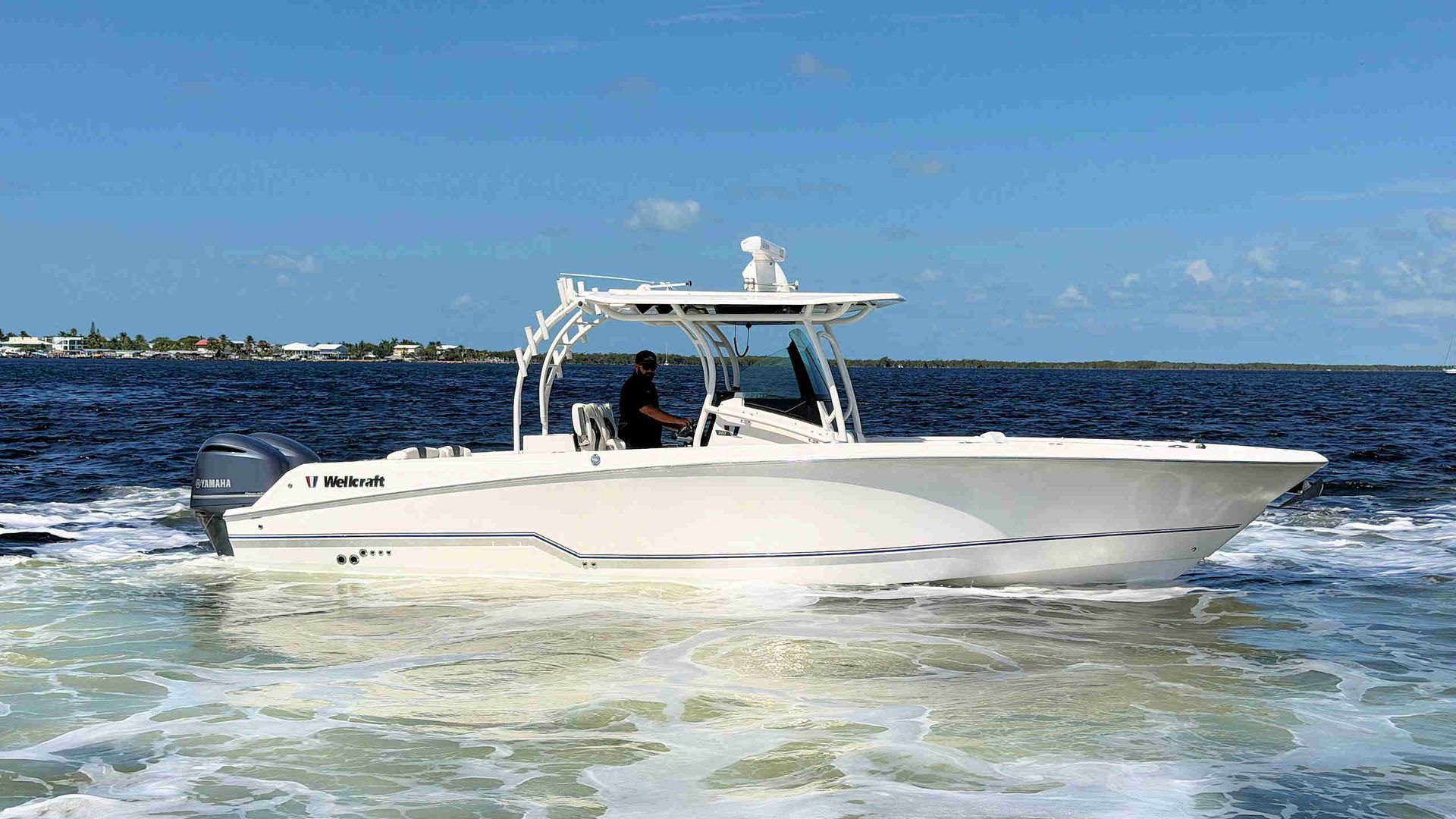 White center-console speeding across choppy blue water under a sunny sky